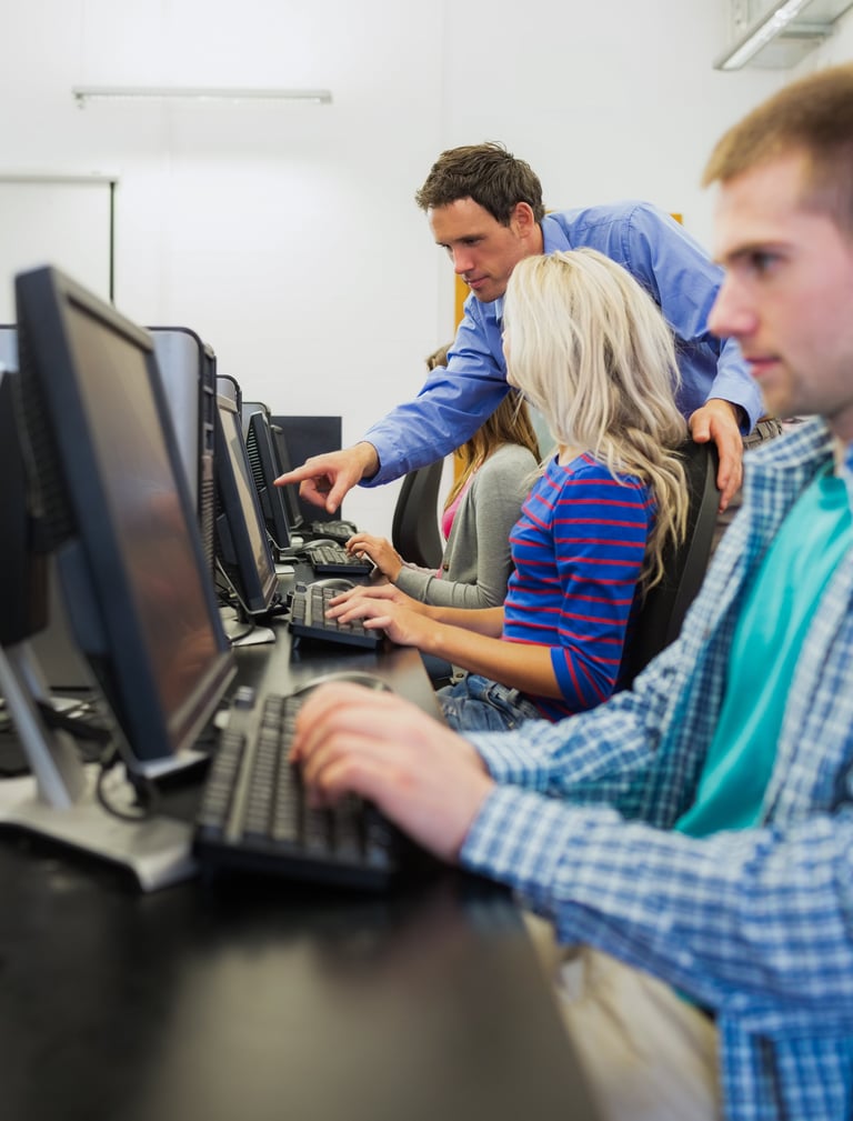 Instructor teaching students at computer workstations in a classroom lab setting